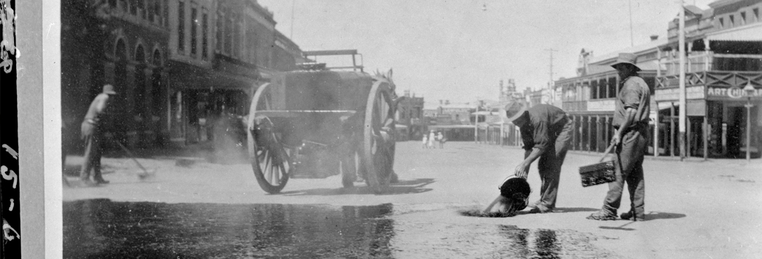black and white photo of men pouring water on road